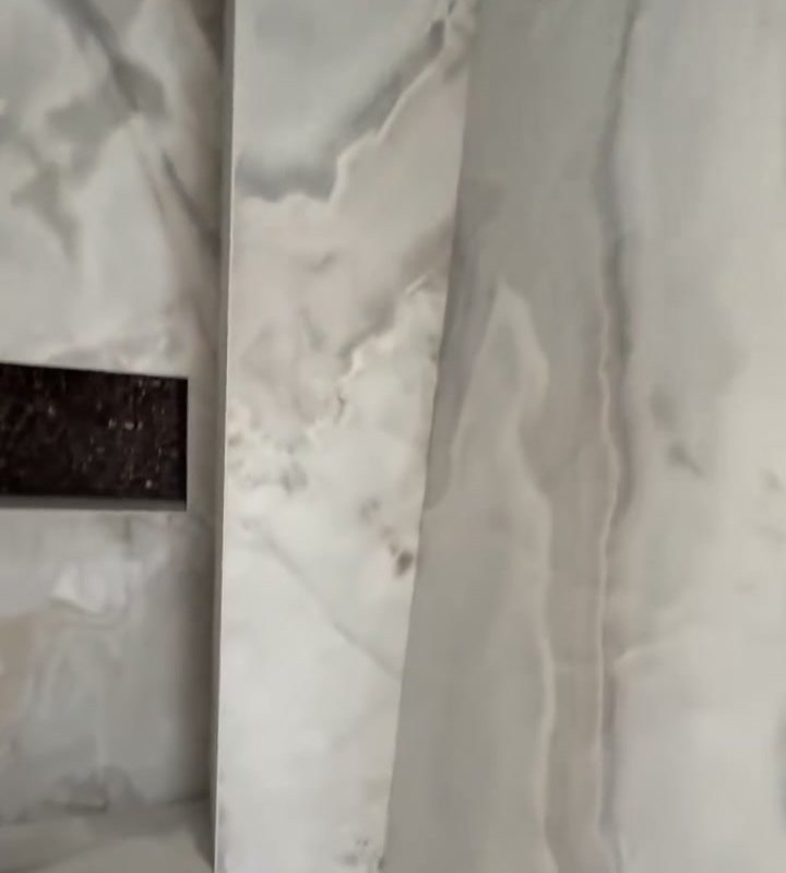 Betegelde badkamerwand met marmerlook tegels en een nis