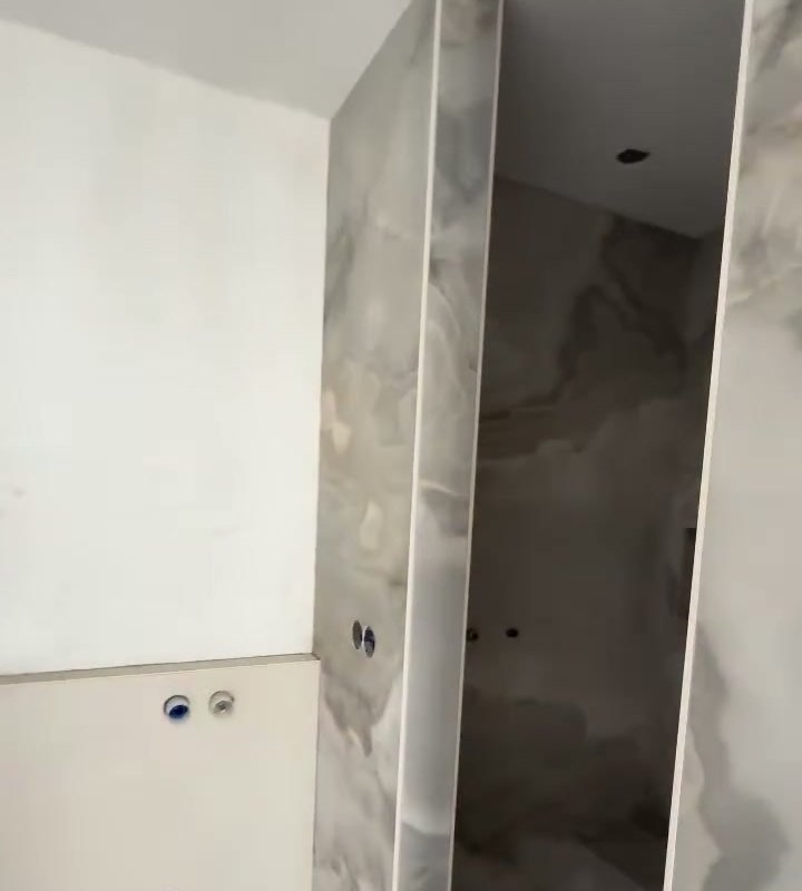 Badkamer in Haarlem met wanden in grote marmerlook tegels, net betegeld