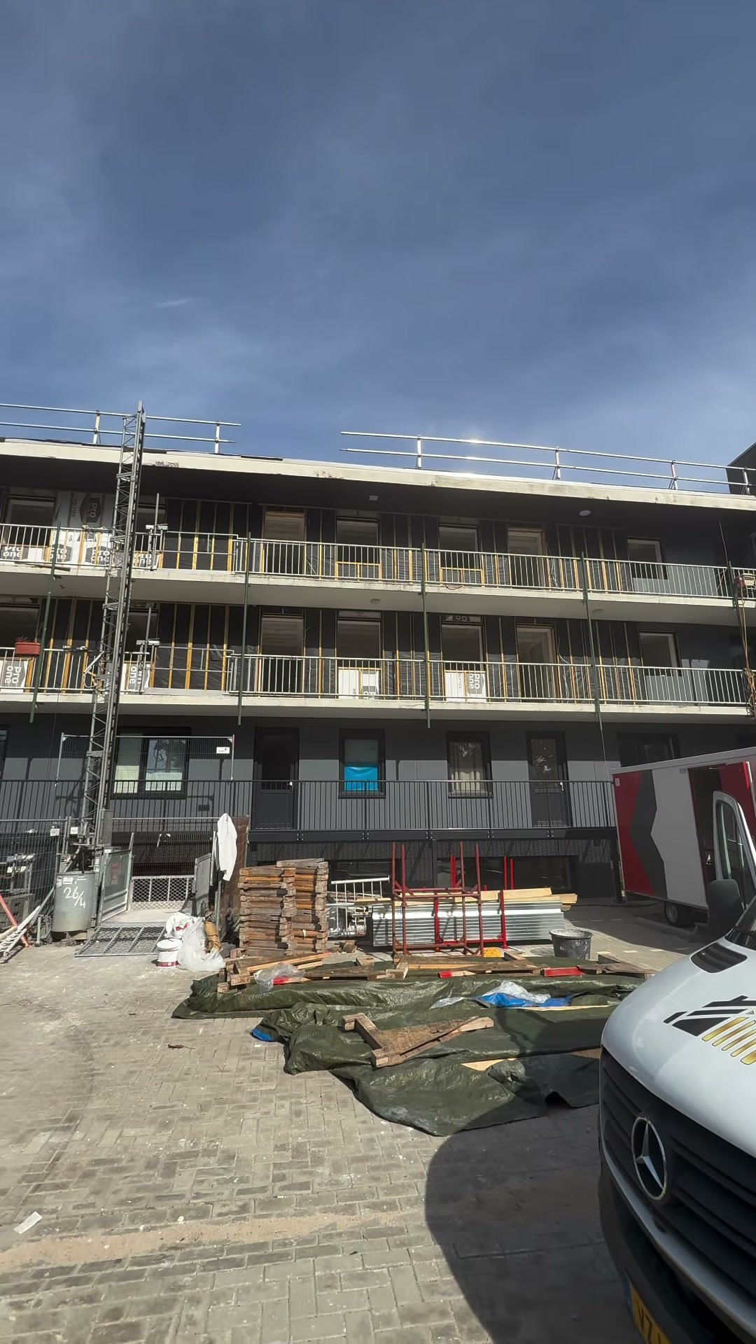 Appartementengebouw in aanbouw met steigers en bouwmateriaal op het terrein