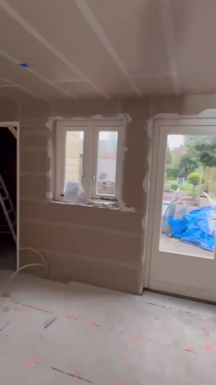 Woonkamer met vers glad gestuukte wanden en plafond en openslaande deuren naar de tuin